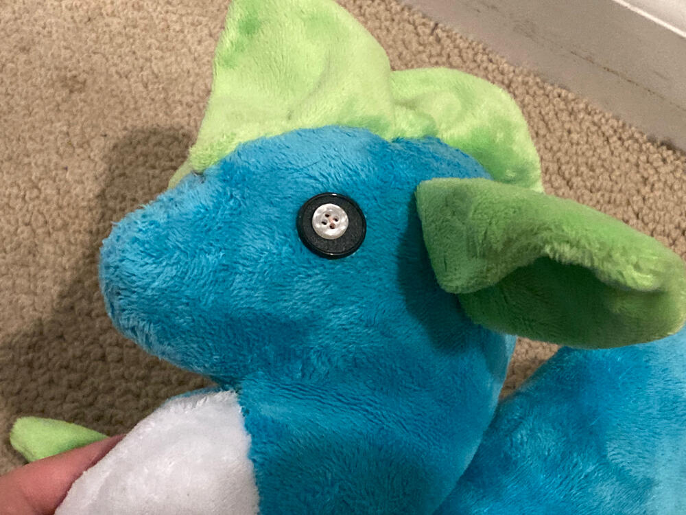 Sea serpent plush face close up, has button eyes &amp; a round nose
